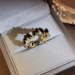 Detailed view of gold-plated irregular zircon ring with black gems in a gray jewelry box