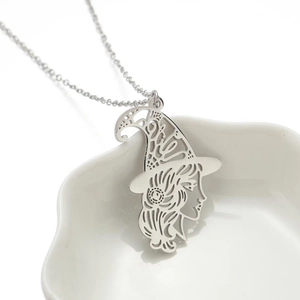 Halloween witch silhouette pendant on a silver stainless steel necklace over white porcelain