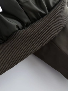 Macro detail of dark olive green bomber jacket showing ribbed cuff and woven fabric texture