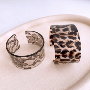 Detail of wide acrylic open cuffs featuring black lace and classic leopard print patterns