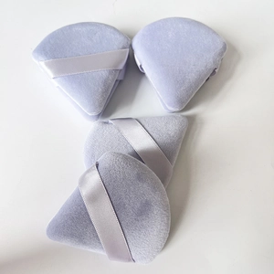 Set of four purple triangle velvet powder puffs with ribbon handles on a white background