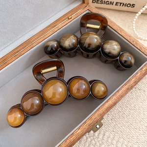 Detailed view of resin geometric hair claw clips with gradient beads in a jewelry box