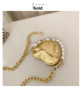 Détail d'un mini sac doré en forme de cœur avec texture serpent et anse en perles