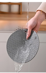 Close-up of grey silicone heat-resistant mat with sea wave pattern being washed under water