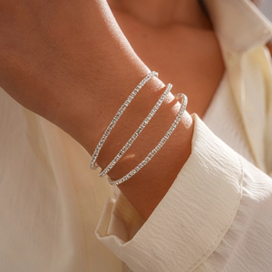 Detailed close-up of a silver-toned triple layered tennis bracelet with shimmering crystals