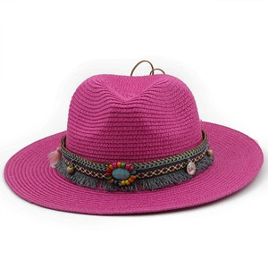 Detail of bohemian ethnic beads, blue stone, and gray tassels on magenta straw fedora hat