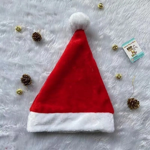 Close-up of red plush Christmas hat with white faux fur trim and golden bell decorations