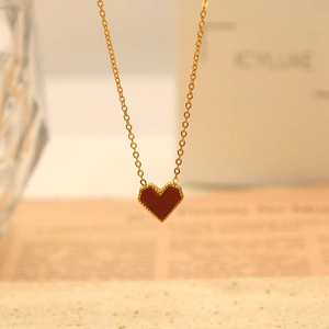Macro view of red heart pendant with gold beaded edges on a delicate gold chain