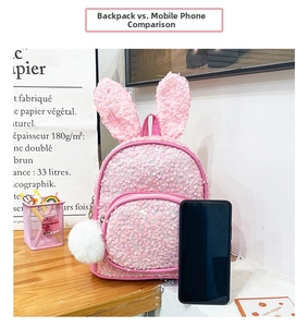 Pink sequin backpack with cute rabbit ears and fluffy pompom next to phone for size reference