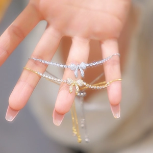 Close-up of adjustable gold and silver bow bracelets featuring sparkling zircon stones