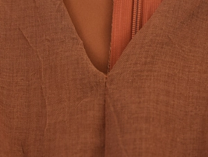 Close-up of brown cotton linen fabric texture and invisible zipper detail on the dress