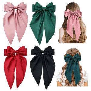 Detailed views of satin bow hair clips in multiple colors with long trailing ribbons