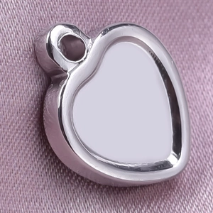 Close-up of heart-shaped stainless steel pendant base for DIY jewelry making on pink silk