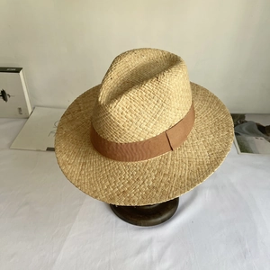 Close-up of the woven texture on a raffia straw hat with a brown decorative band