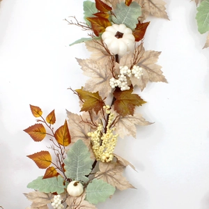 Close-up of fall garland with white pumpkins, maple leaves and berries on white background