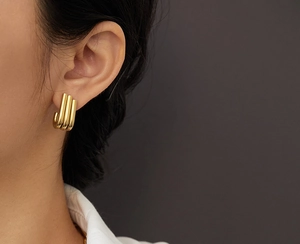 Close-up of elegant gold triple tube J-shaped earrings for women in polished finish