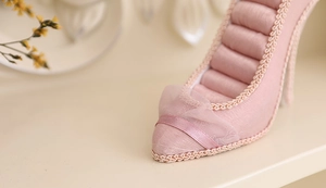 Detailed close-up of pink high heel jewelry display stand with lace and ribbon bow