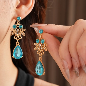 Detail of vintage gold flower earrings with blue crystal teardrops on a model