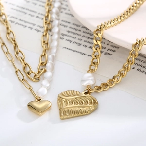 Double-layered golden necklace with freshwater pearls and textured heart pendants