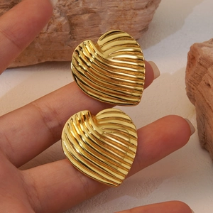 French chic gold heart stud earrings with textured pleated design on a rock display