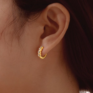 Close-up of gold hoop earrings with four round crystals on female model's ear