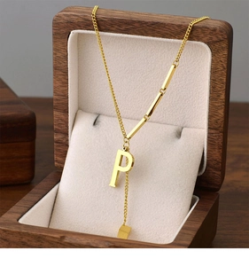 Macro detail of a golden titanium steel necklace with P pendant in a wooden jewelry box