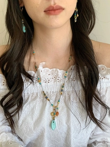 Detail view of turquoise beaded necklace and earrings set worn by a model