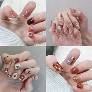 Detail showing four styles of press-on nails including floral and amber gradient designs