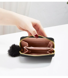 Detail of short black wallet featuring pink lining, multiple card slots and gold zipper