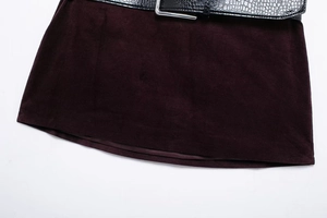 Détail de la jupe en velours bordeaux avec ceinture effet croco et boucle métallique