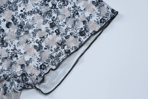 Detail of floral print jumpsuit showing mesh fabric texture and reinforced overlock stitching