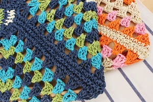 Close-up of colorful crochet details on a multi-color woven paper straw vacation bag