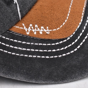 Detail der mehrreihigen Kontrastnähte auf grauem Stoff und braunem Wildleder-Cap