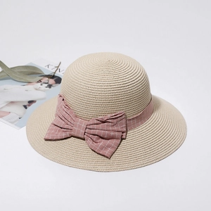 Detail of beige straw sun hat featuring a light pink checkered bow for summer