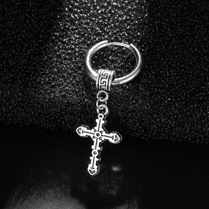 Macro shot of a black stainless steel gothic cross earring on textured background