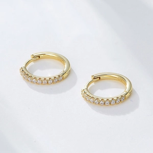 Detailed close-up of 925 sterling silver huggie earrings with gold finish and zircons
