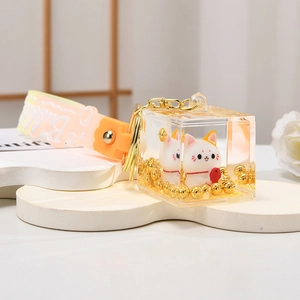 Close-up of lucky cat acrylic cube keychain with liquid oil and golden decorative beads