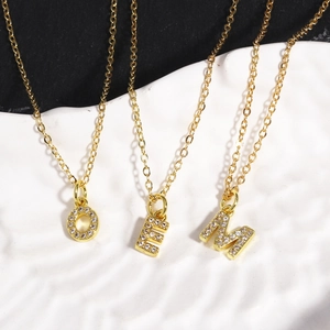 Close-up of gold letter O E M pendants with cubic zirconia on elegant chains