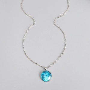 Detailed macro view of a luminous moon pendant with a polished glass cabochon finish