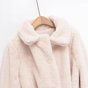 French style cream faux fur jacket with lapel collar and waist belt hanging on a hanger