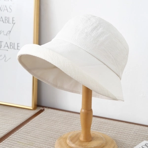 Minimalist beige cotton linen sun bucket hat for women on a wooden display stand
