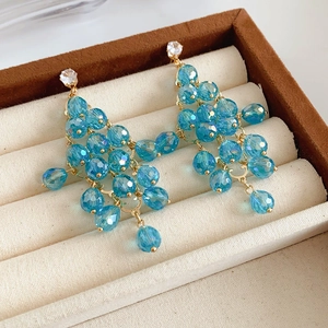 Detailaufnahme von blauen Kristall-Ohrringen mit goldenen Akzenten in einer Schmuckschatulle