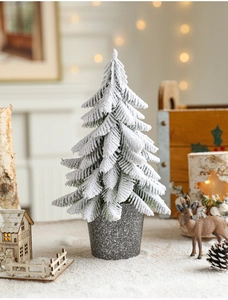Close-up of a mini flocked Christmas tree with snow in a grey stone pot for desktop decor