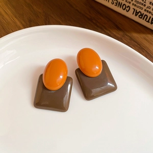 Retro resin flower earrings with orange oval and brown square studs on a white plate