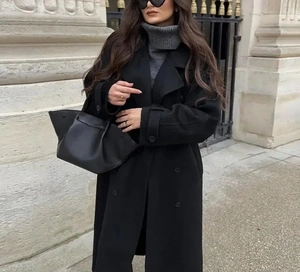 Détail d'un manteau en laine noir pour femme avec col roulé gris et sac à main en cuir