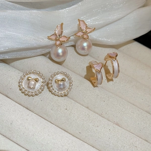 Détail de l'ensemble de boucles d'oreilles avec papillons roses et perles élégantes