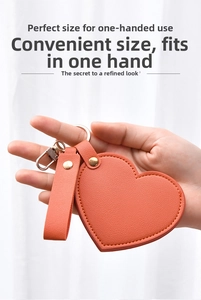 Handheld heart-shaped orange leather pocket mirror with gold metal keychain hardware