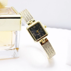 Detail of square black dial watch with gold crystal-encrusted bangle and perfume bottle