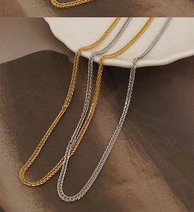 Vue macro de colliers en maille Chopin en acier inoxydable doré et argenté sur un plat
