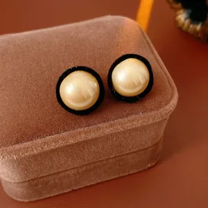 French vintage round pearl earrings with black velvet trim on a brown jewelry box
